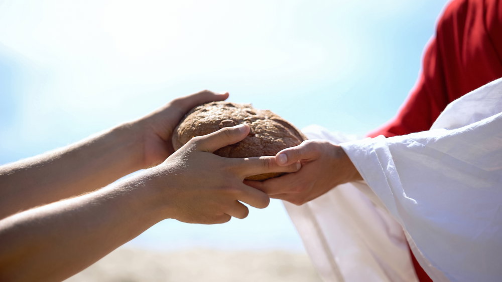 Manos de Jesús dando pan a los pobres