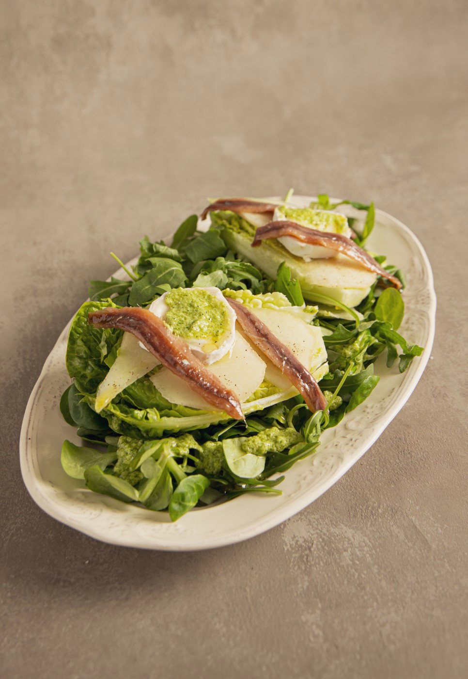Ensalada de pera y anchoa con pesto de rúcula y canónigos