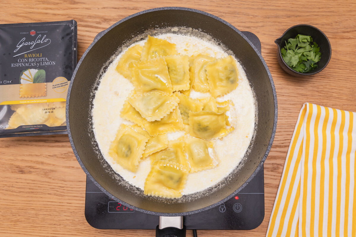 Raviolis rellenos de espinacas con salsa de ajo, queso y espolvoreado con beicon crujiente