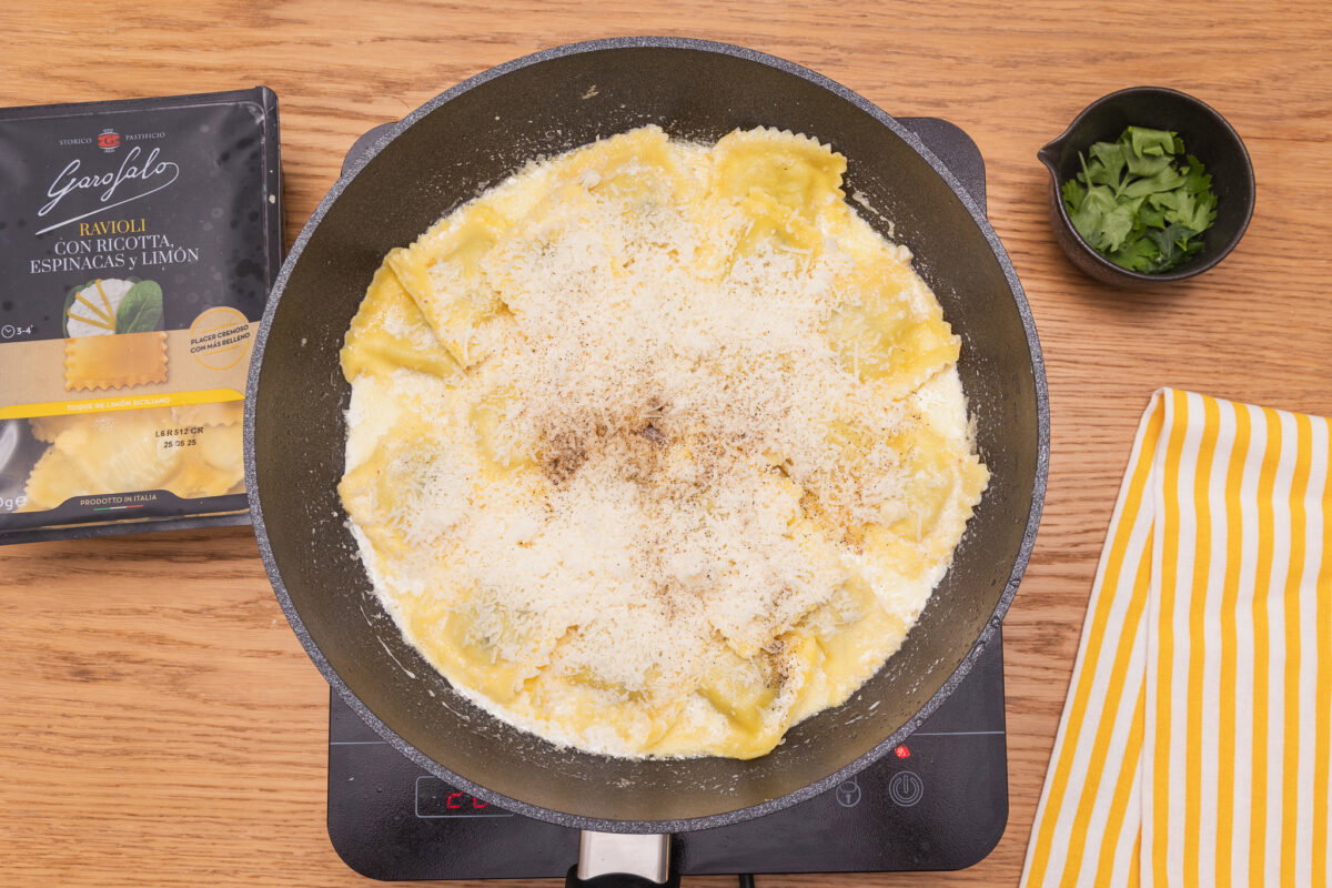 Raviolis rellenos de espinacas con salsa de ajo, queso y espolvoreado con beicon crujiente