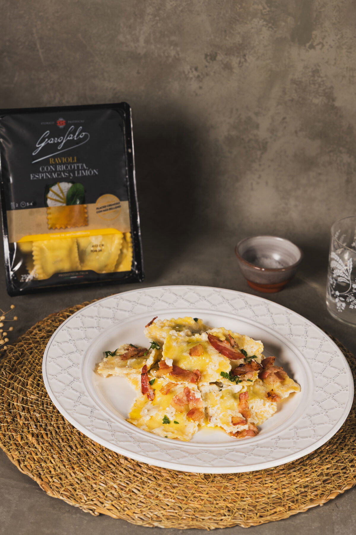 Raviolis rellenos de espinacas con salsa de ajo, queso y espolvoreado con beicon crujiente