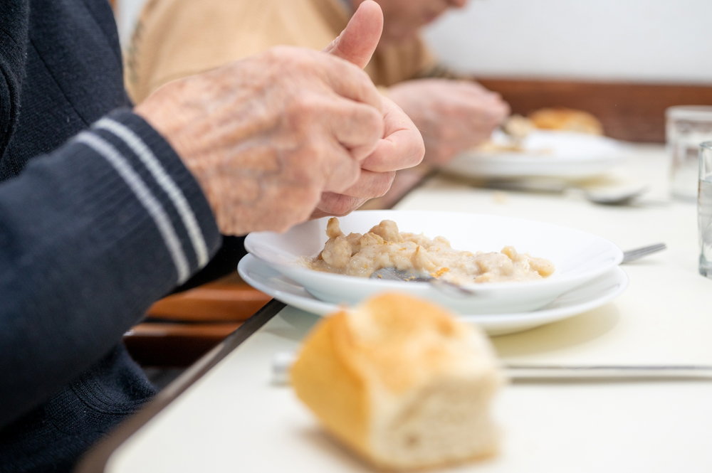 Hombre anciano comiendo con pan